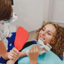 The dentist comparing patient's teeth shade with samples for bleaching treatment